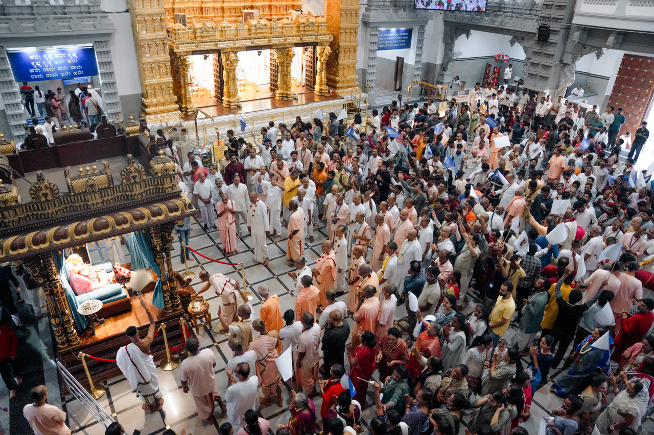 View of the temple hall — Sri Sri Radha Krishnachandra darshan with hundreds of devotees gathered to receive the news