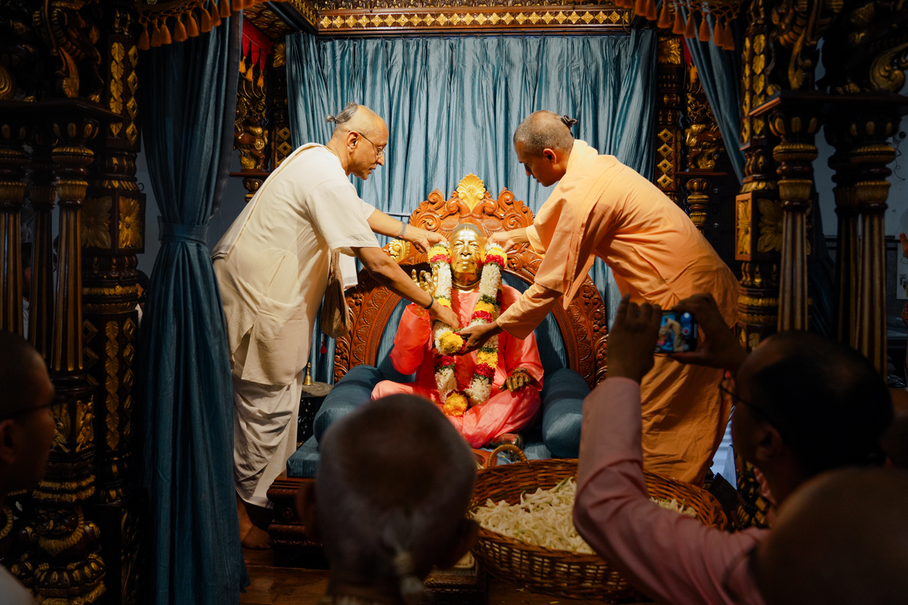 Sri Madhu Pandit Dasa holding the Supreme Court judgement aloft, garlanded and surrounded by devotees with raised arms and flags